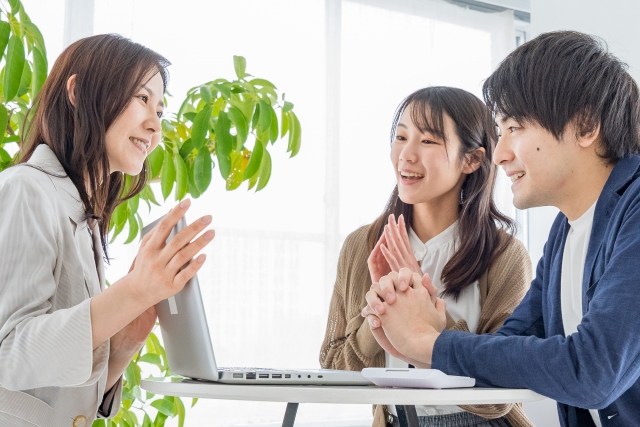 若い夫婦と話す女性スタッフ